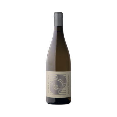 Bottle of Susana Esteban Vinyle Branco 2023 next to a vinyl record and glass of white wine, evoking the wine’s musical inspiration and refined elegance. Set against a mountainous backdrop suggestive of Serra de São Mamede.